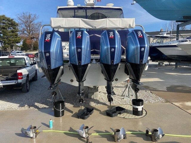 Four outboard boat engines being serviced with propellers removed during winterization and seasonal maintenance at a marina