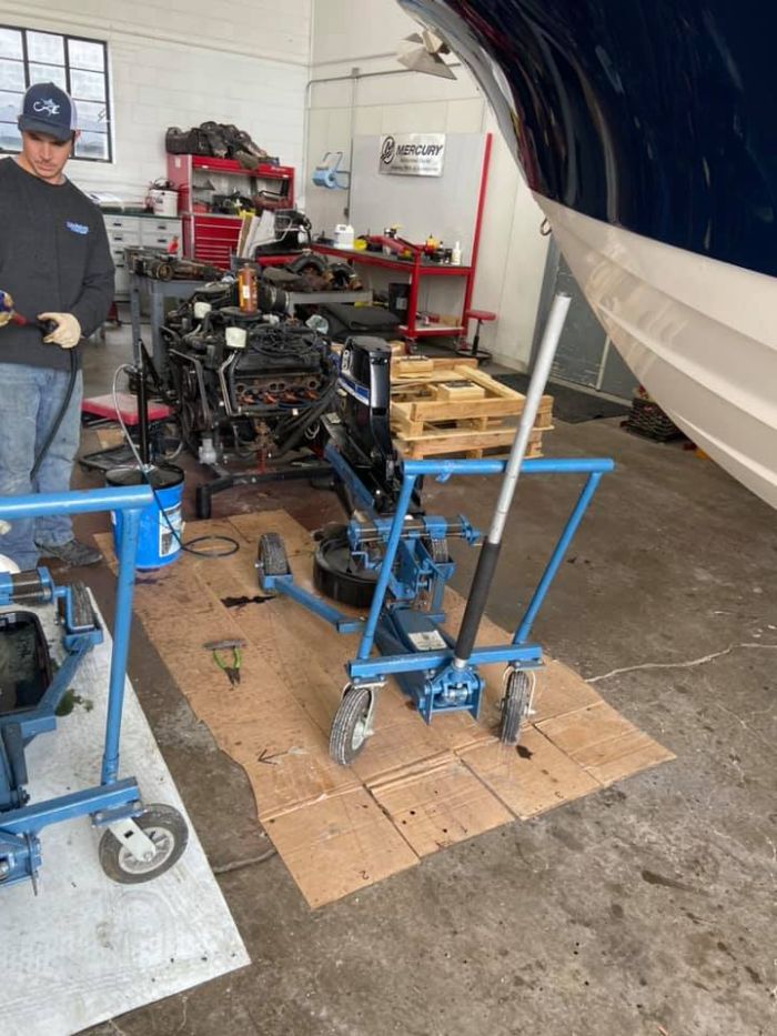 Marine technician servicing a boat engine during winterization inside a marina repair facility