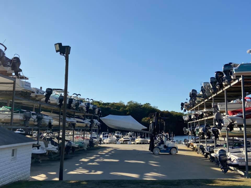 Boats stored on multi-level dry stack racks at a marina with a marine forklift in the storage yard