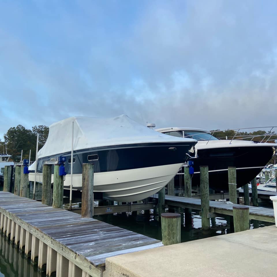 Powerboat partially shrink-wrapped at a marina dock for winter protection and seasonal storage